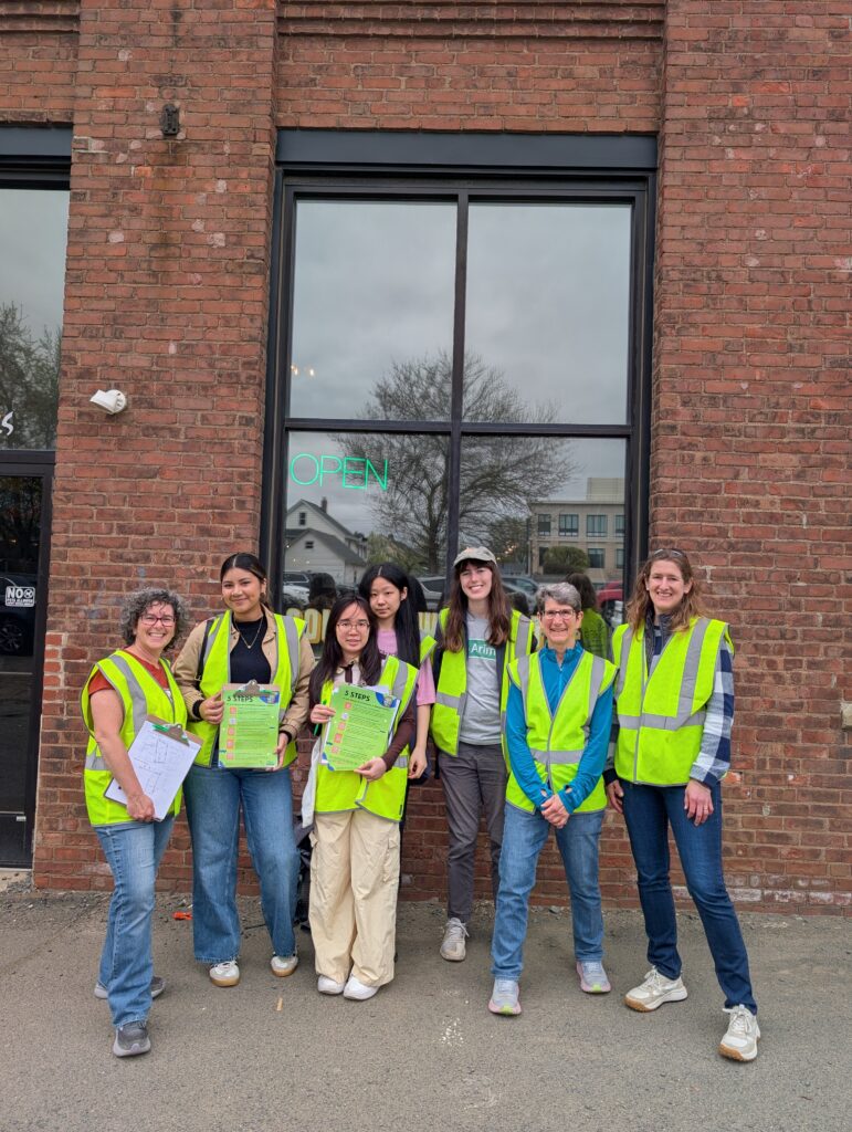 Group of people with Jonah Center Safety Vests, smiling in front of brick building