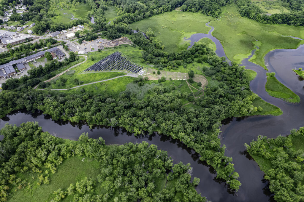 Overhead view of the hill with solar panels, surrounded by vegetation and two rivers. 